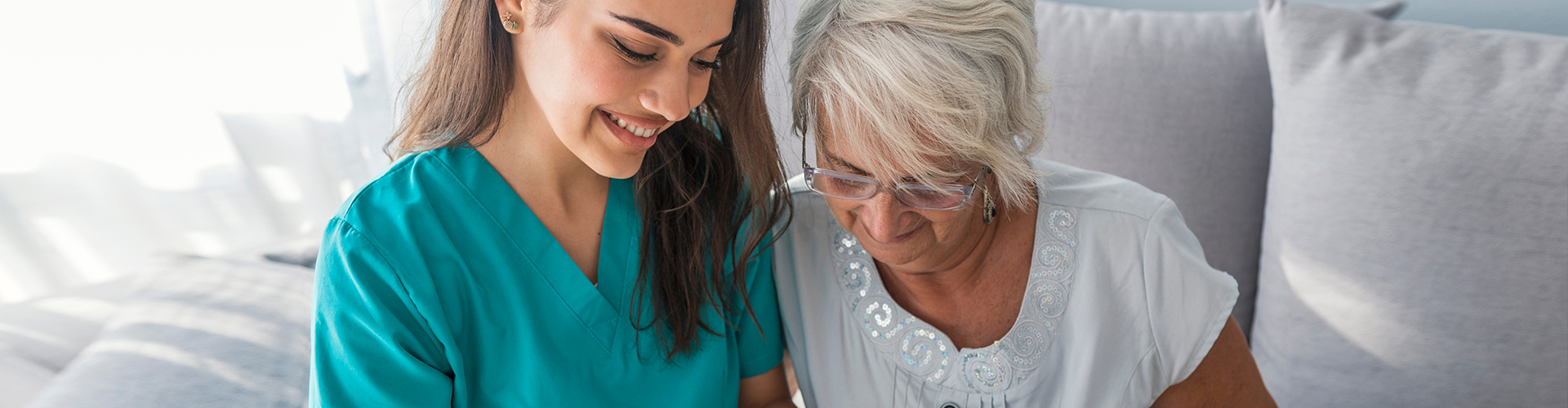 caregiver and an elderly woman reading
