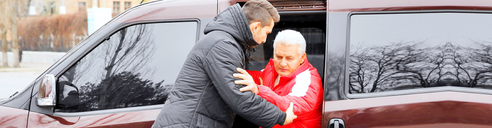 caregiver helping an elderly man get out of the vehicle